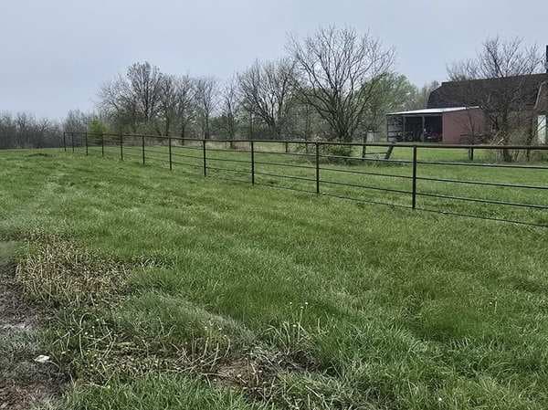 Pipe and wire pasture fencing near a barn